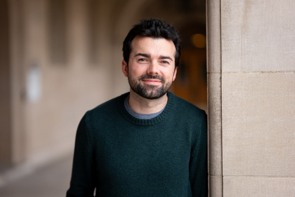 KJ Schaeffner smiles for a photo while leaning against a pillar outside Ridgley Hall