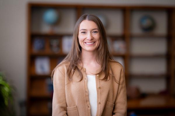 Samantha Stevenson smiles for a photo in front of a bookshelf.