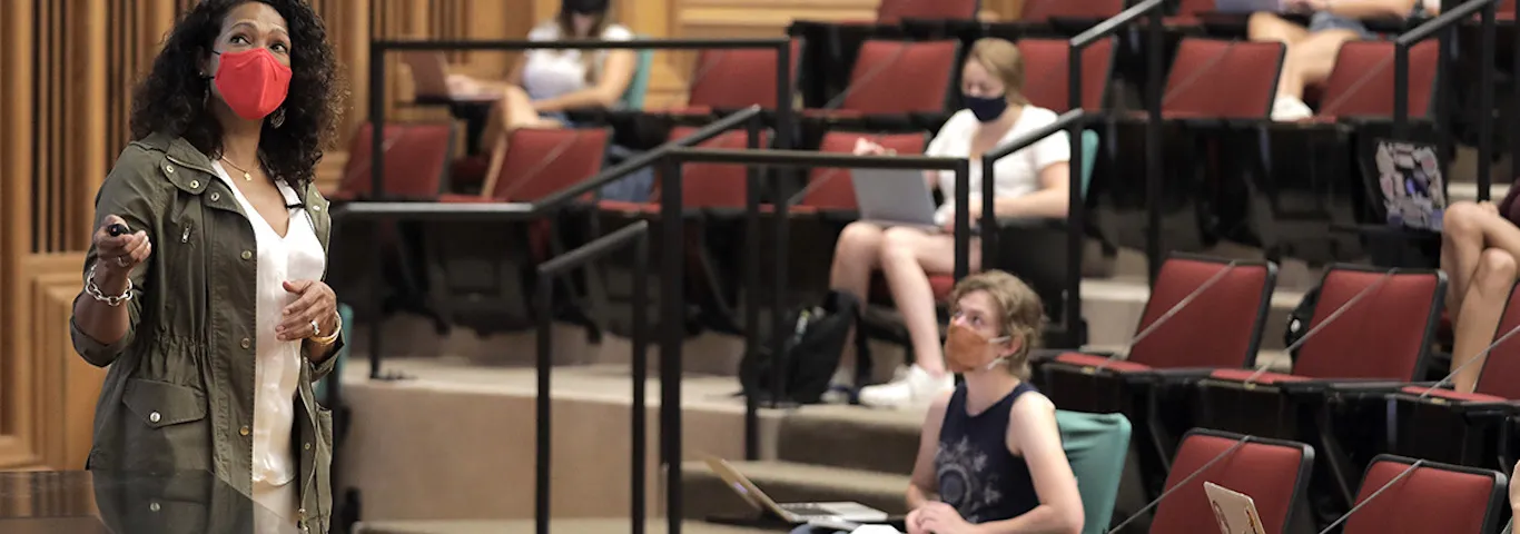teacher in mask giving lecture to students