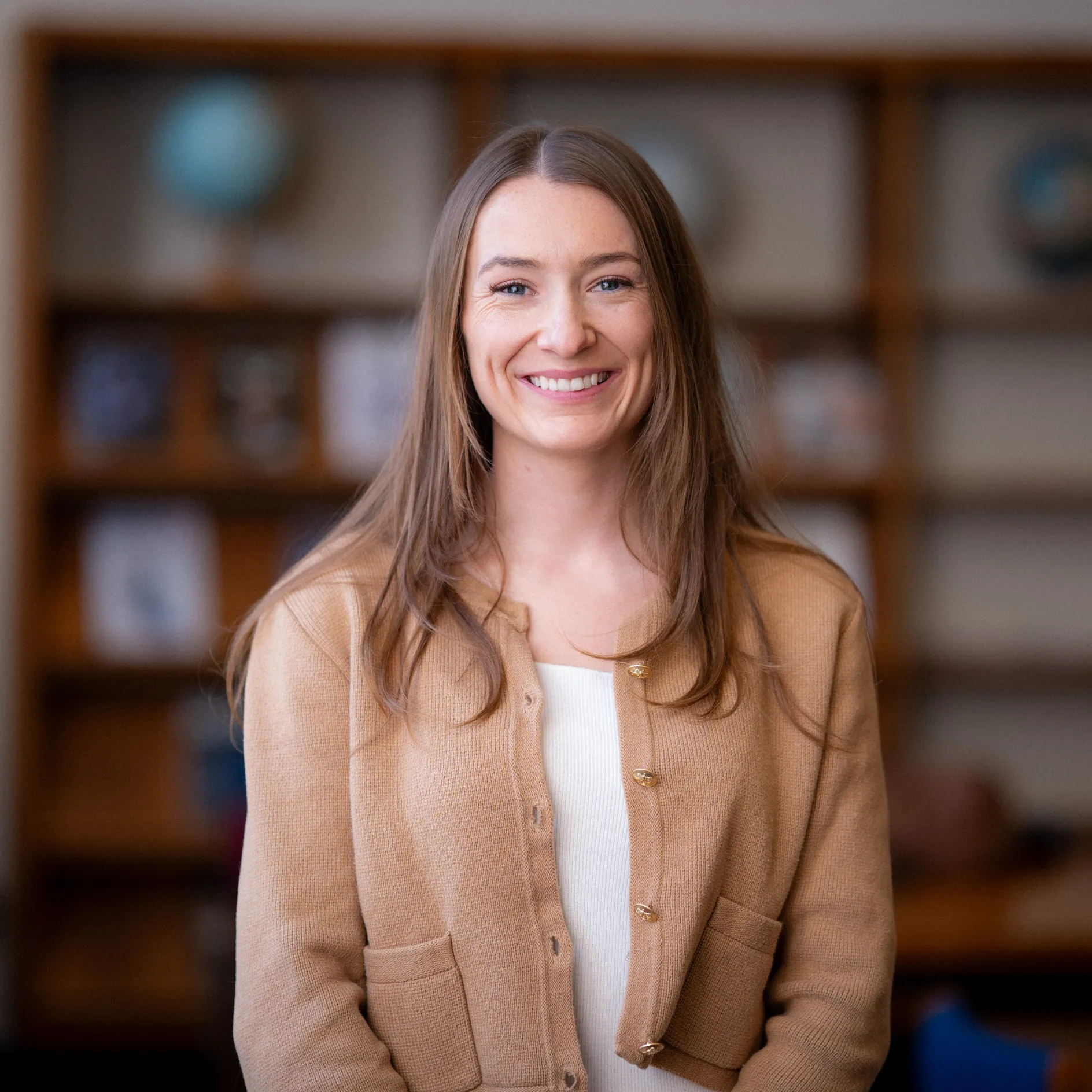 Samantha Stevenson smiles for a photo in front of a bookshelf.